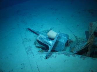 Stbd anchor embedded in steel plate from ship's side in debris field